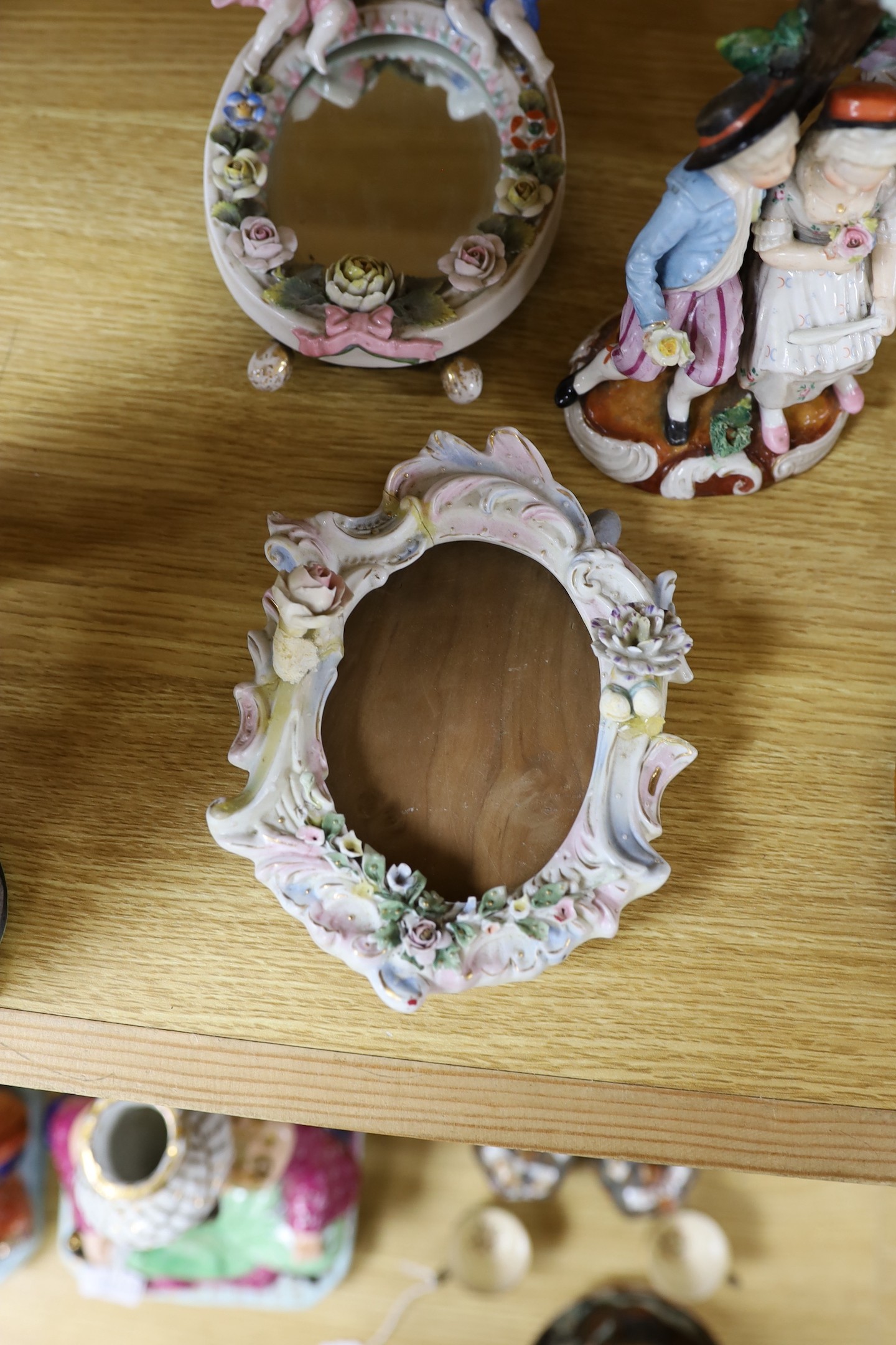 A pair of 19th century continental porcelain figural candlesticks and a group of four similar frames